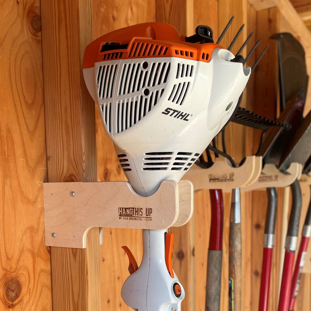 Wood hook holding a string trimmer on a shed wall