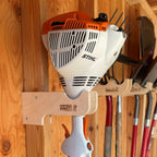 Wood hook holding a string trimmer on a shed wall