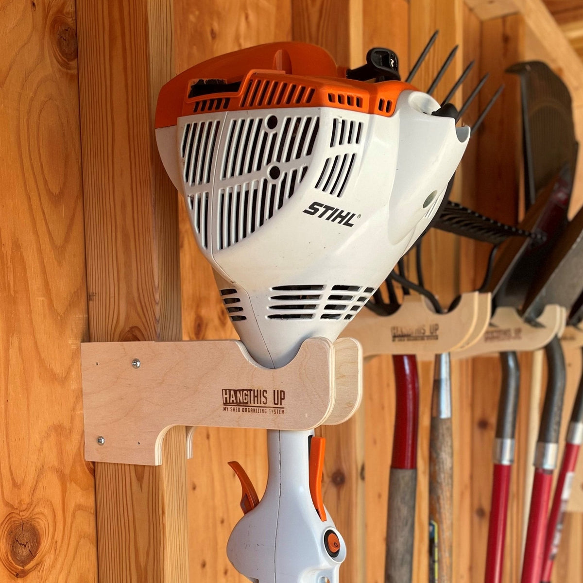 Wood hook holding a string trimmer on a shed wall