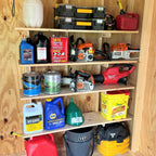 Shed shelves holding oil, paint cans, tool cases and gas cans