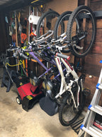 Garage wall with bikes hanging on the rack above a lawn mower