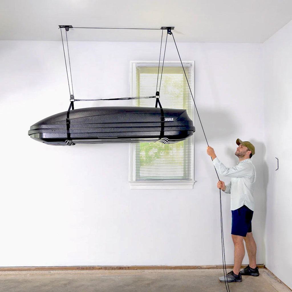 Man raising a cargo box to the ceiling with the hoist rope