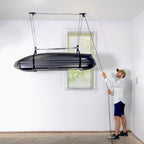 Man raising a cargo box to the ceiling with the hoist rope