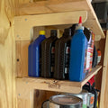 Shed shelf holding motor oil and fluids on wood brackets