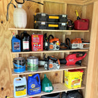 Shed shelf brackets holding paint cans, tool cases and supplies on a wooden shed wall