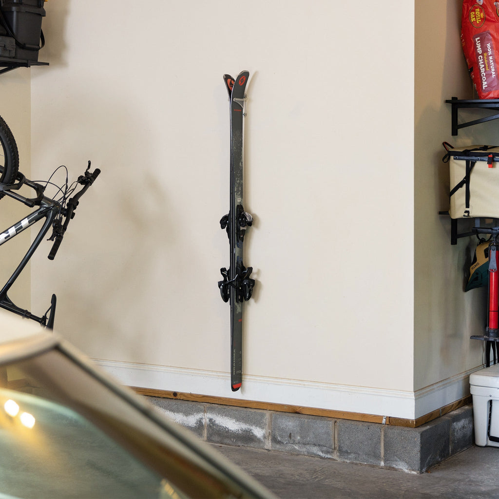 Pair of skis stored vertically on a clear Summit wall rack in a garage