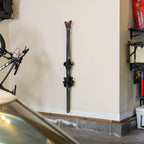 Pair of skis stored vertically on a clear Summit wall rack in a garage