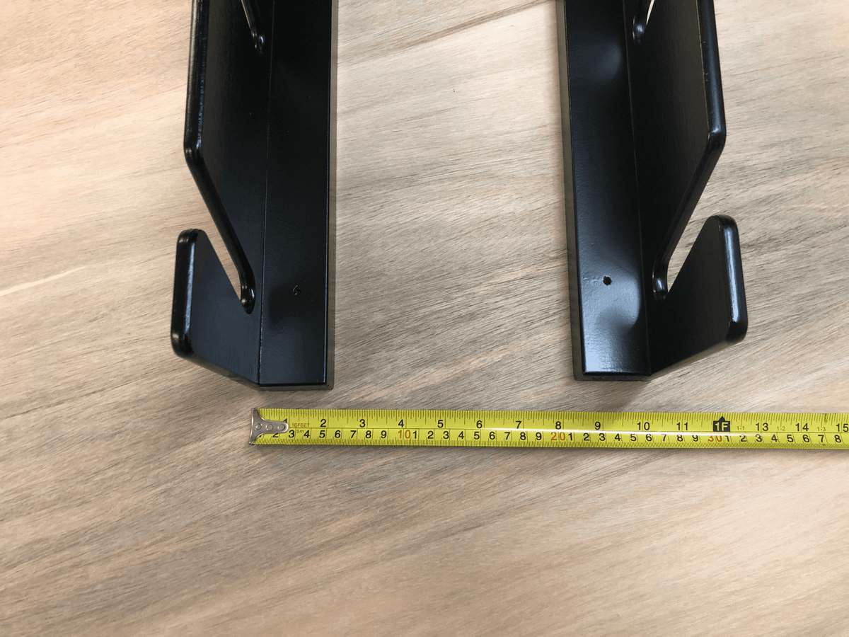 Black ski rack rails with a tape measure showing their spacing