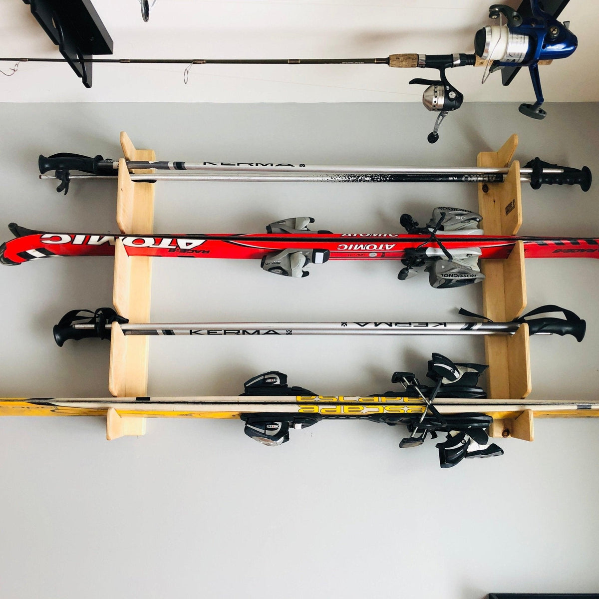 Natural wood ski rack holding skis below a fishing rod rack