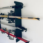 Black ski rack holding skis with bindings