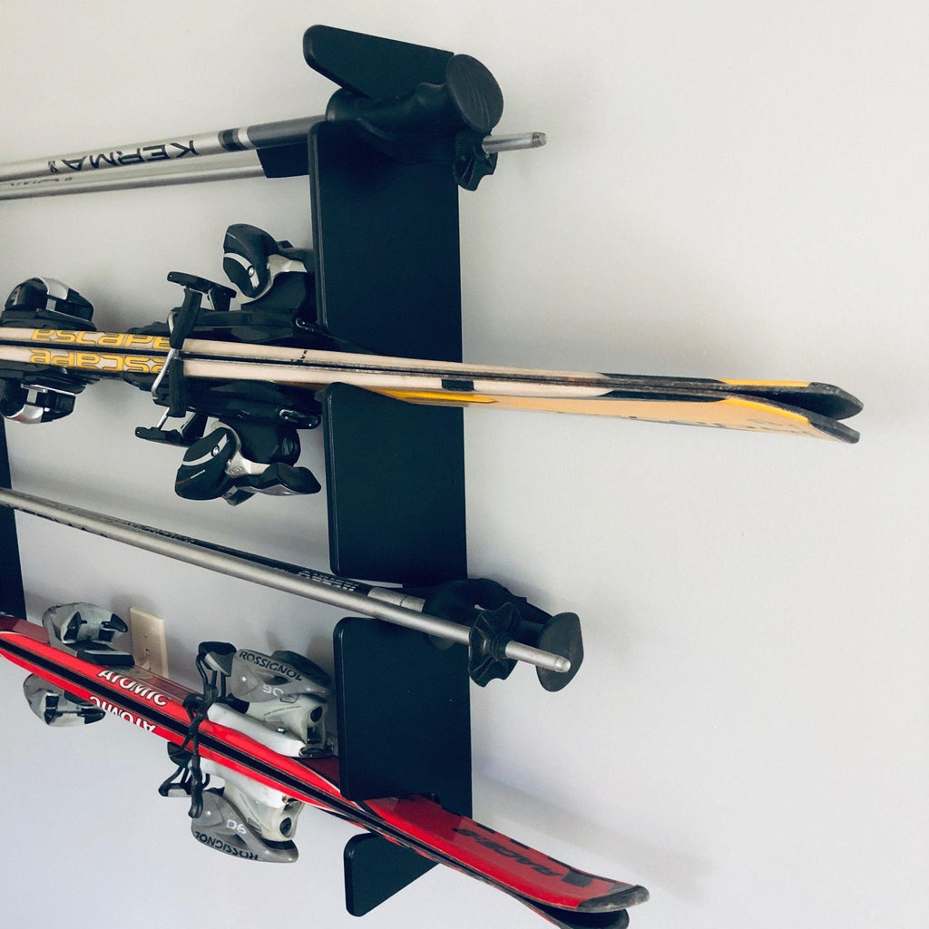 Close-up of skis resting on a black wall ski rack