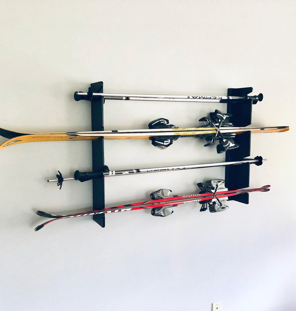 Black ski rack holding four pairs of skis on a wall