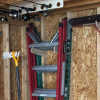 Two stepladders stored on a wall rack under fishing rods