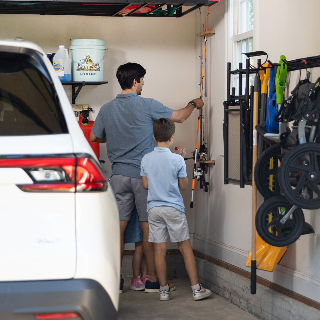 Parent and child taking fishing rods from the wall rack in a garage