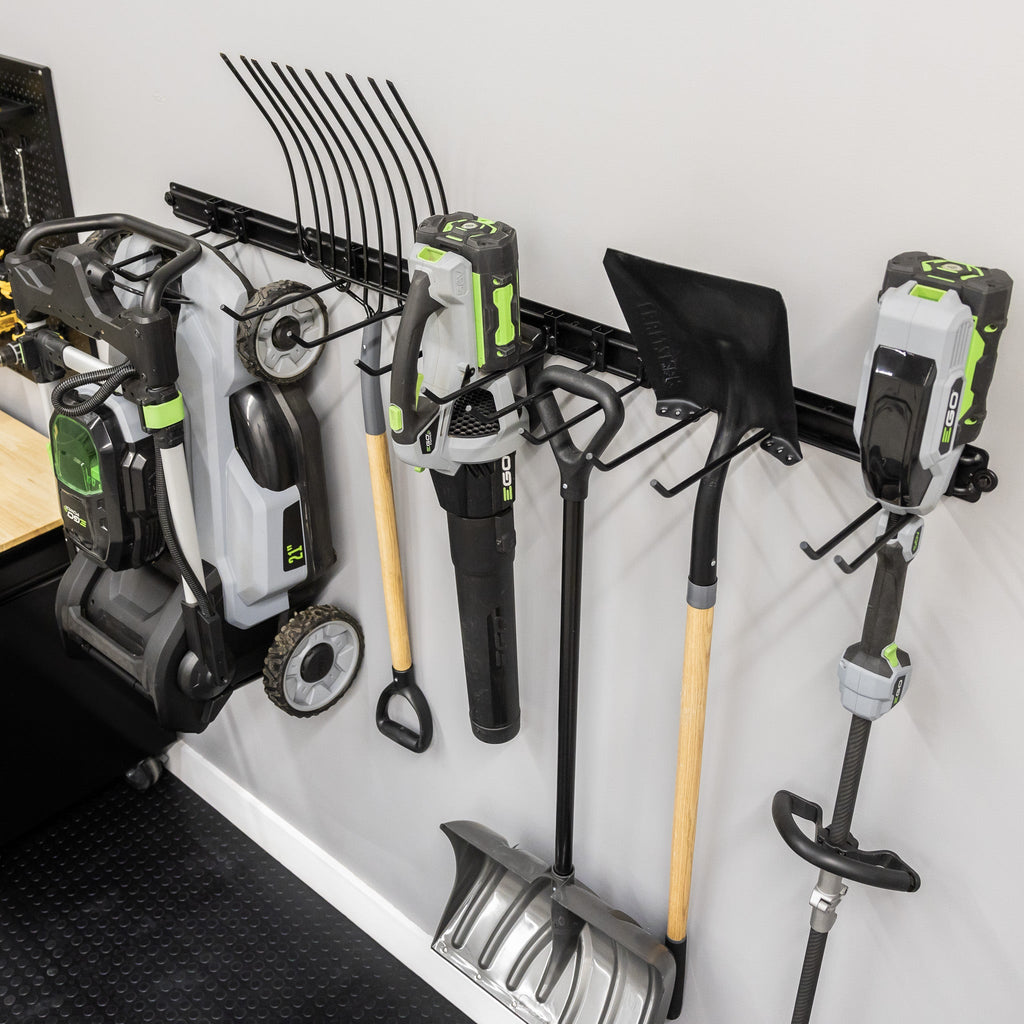 Angled view of yard tools and a mower hung on the 64-inch wall organizer