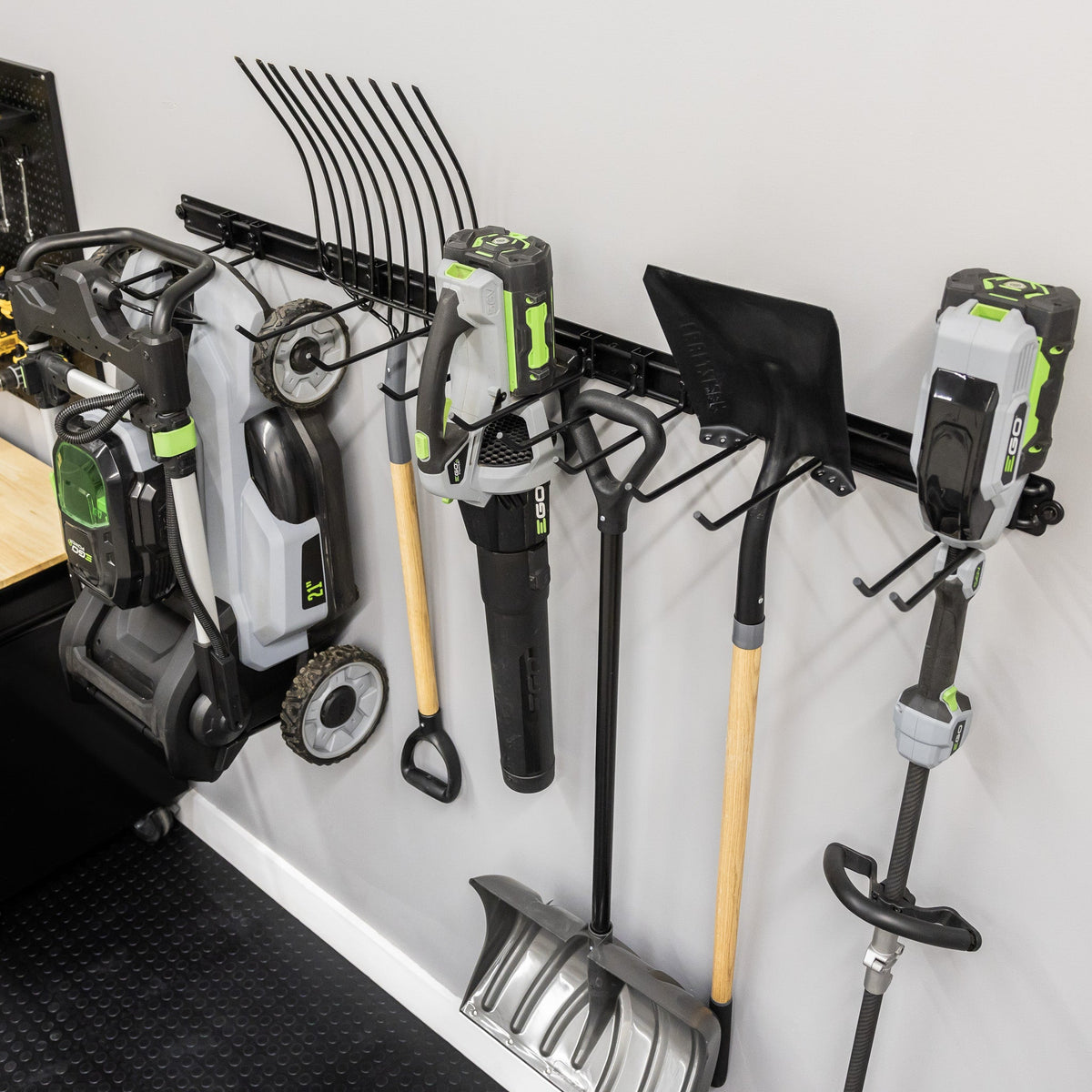 Angled view of yard tools and a mower hung on the 64-inch wall organizer
