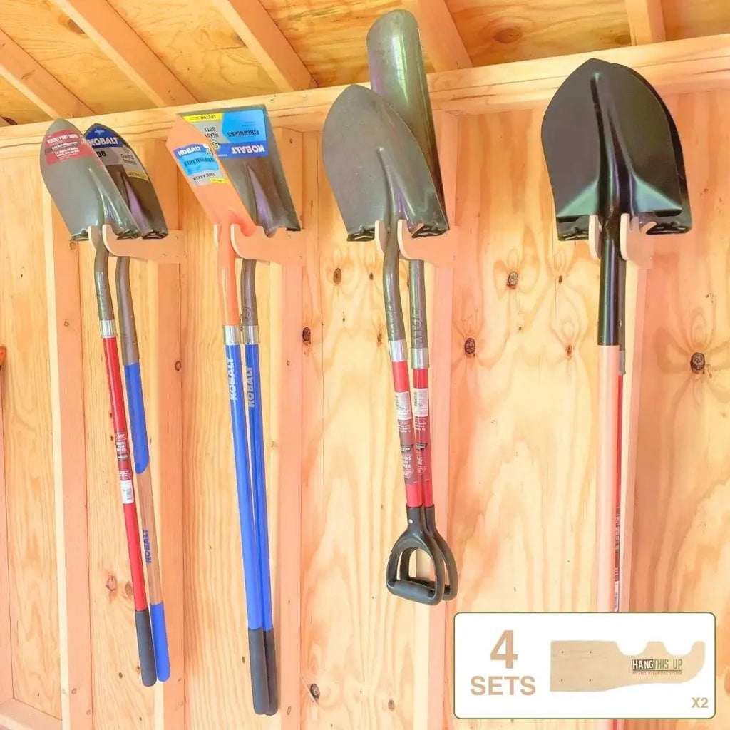 Shovels and a rake hanging on wood tool hooks in a shed
