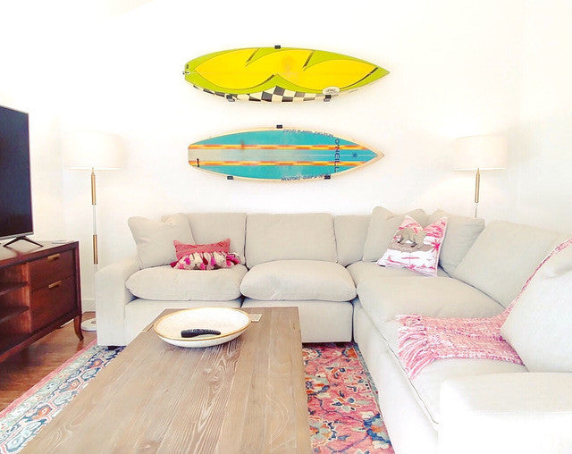 Two surfboards displayed on minimalist wall hooks above a living room sofa