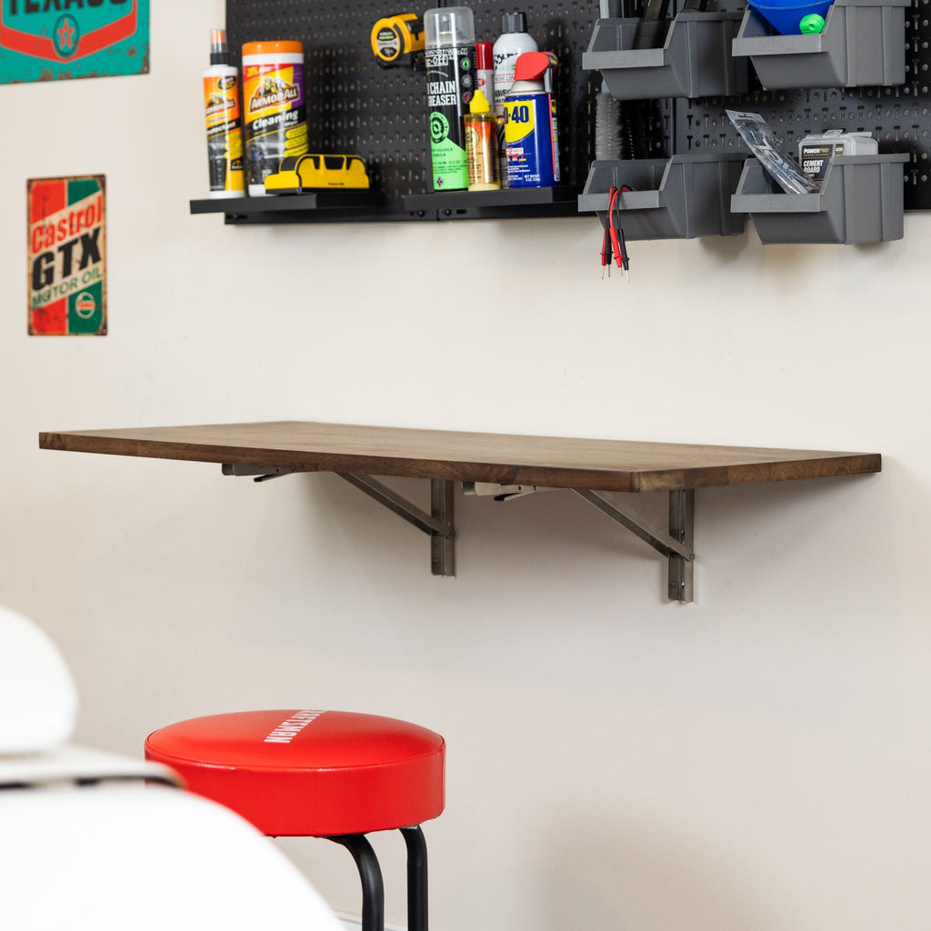 Dark wood folding workbench with stainless brackets below a pegboard