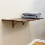 Dark wood folding workbench holding folded blankets