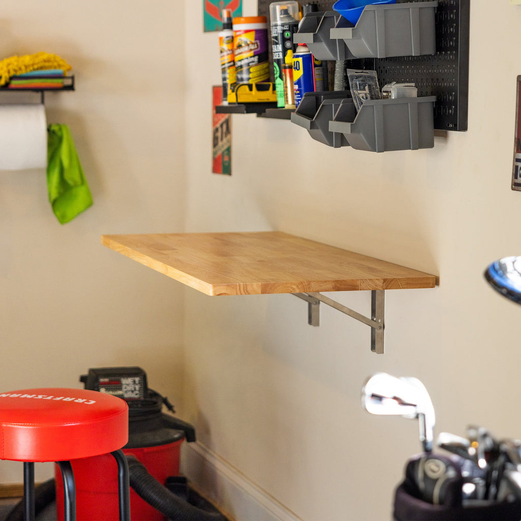 Natural wood folding workbench below a pegboard in a garage