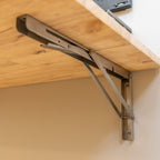 Close-up of the stainless folding bracket under the natural wood top