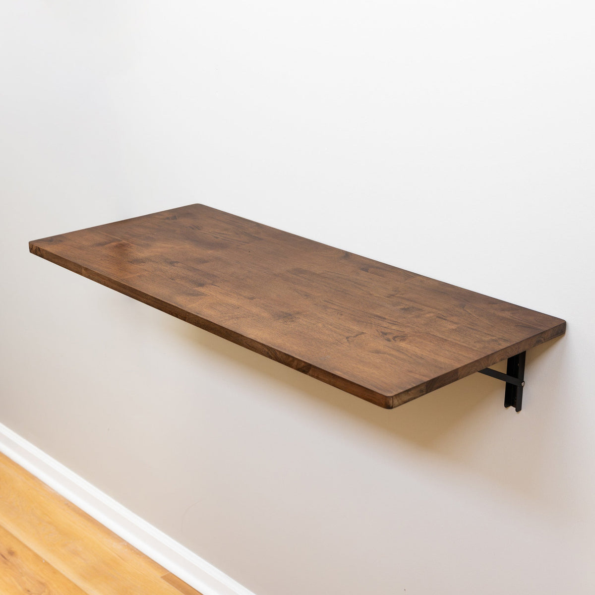 Dark wood folding workbench open on a white wall