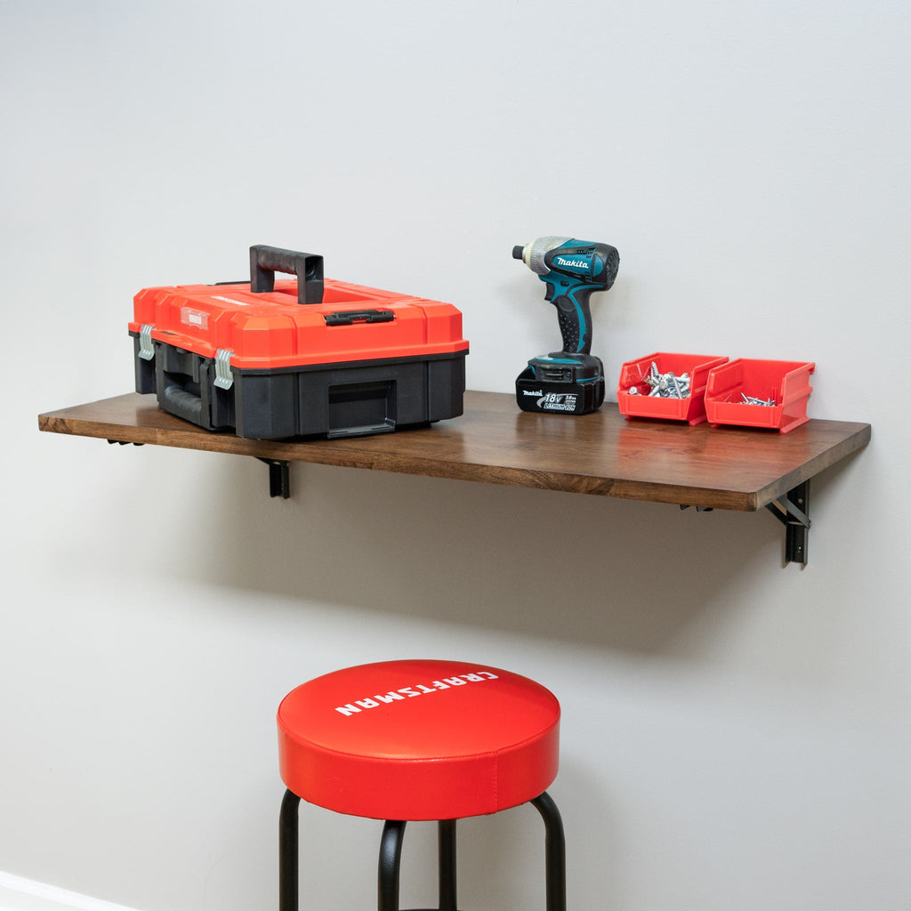 Folding workbench holding a toolbox and drill above a stool