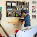 Man working at the natural wood folding workbench under a pegboard
