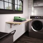 Natural wood folding shelf used for folding laundry beside a washer