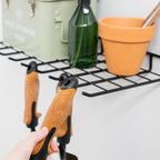 Hand taking a garden trowel from the hooks under the shelf