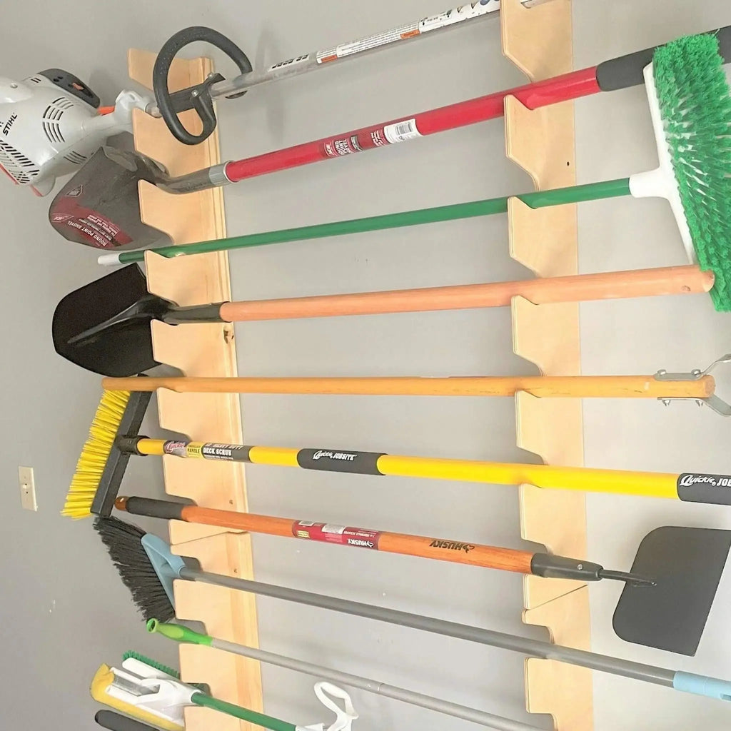 Garden tool rack holding a trimmer, rake, shovel and broom
