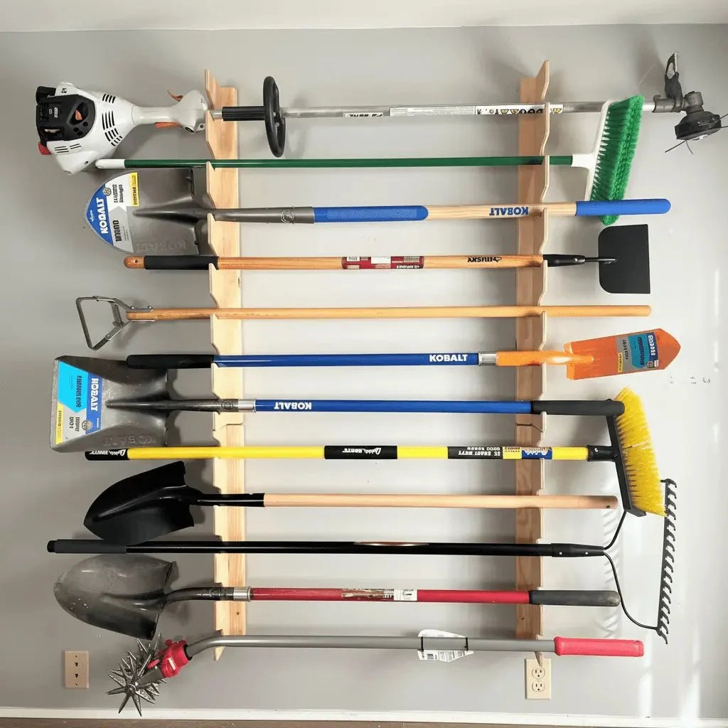 Wall-mounted garden tool rack holding rakes, shovels and a trimmer in a garage