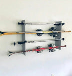 Gray ski rack holding four pairs of skis on a wall