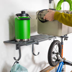 Hand placing a cooler on a gray wall shelf holding a water jug, with a bike hung below