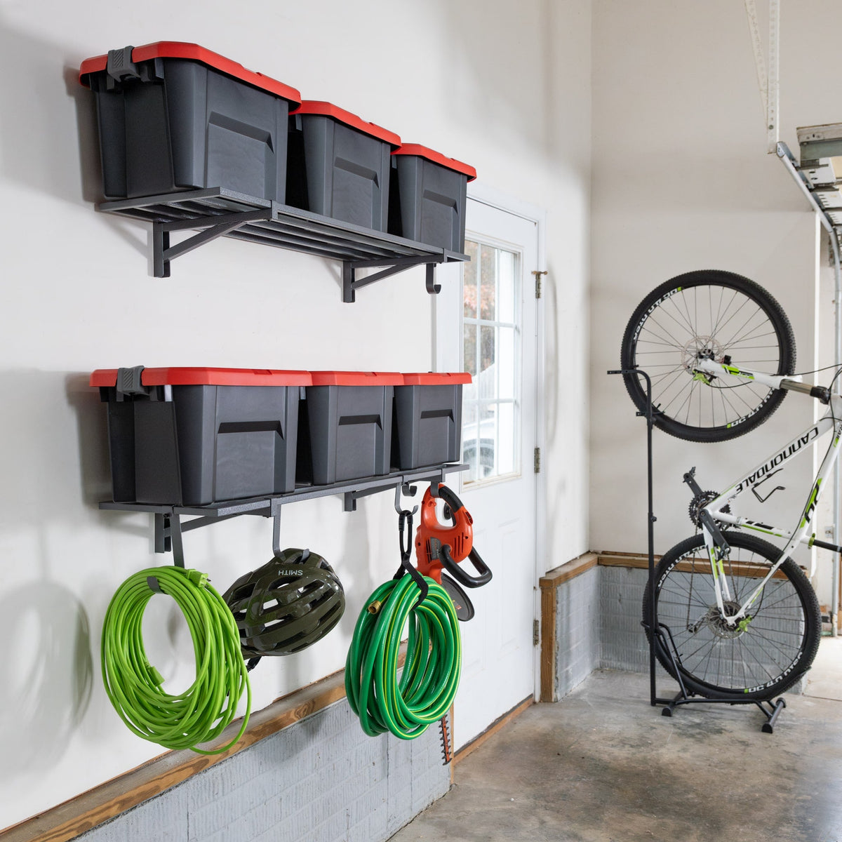 Gray wall shelves holding totes with hoses below, next to a bike stand