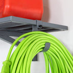 Close-up of an extension cord hanging on a hook under a gray shelf