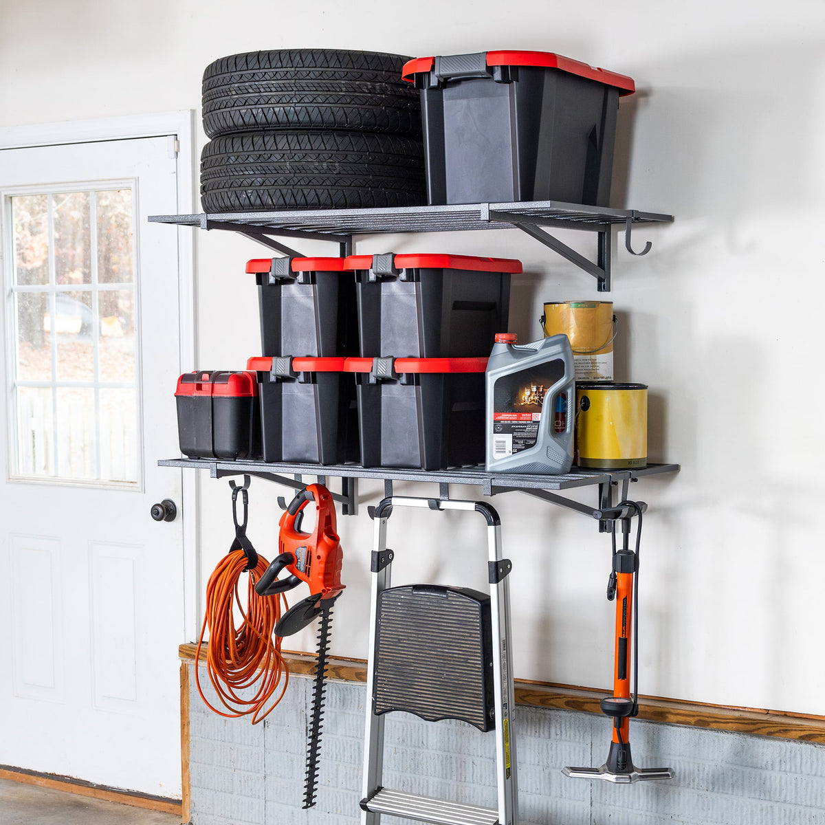 Two gray 2 x 4 ft garage wall shelves holding tires, storage bins, cords and tools