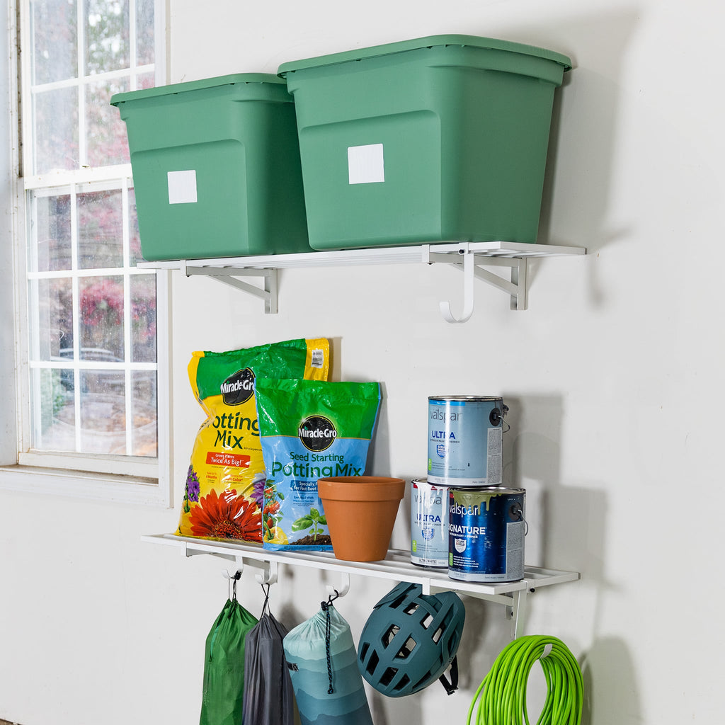Two white 1 x 4 ft wall shelves holding green totes and garden supplies