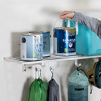 Hand placing a paint can on a white wall shelf with bags hung from the hooks below